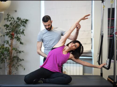 donna che fa esercizi di pilates individuale con fisioterapista