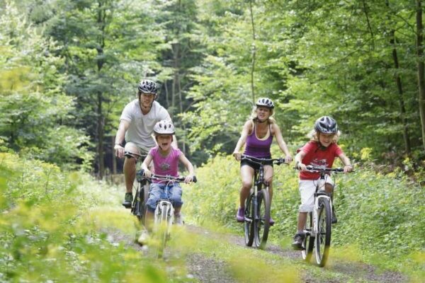 famiglia con bambini che va in bicicletta nei boschi